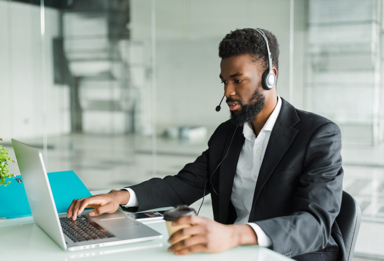 African american customer support operator with hands-free headset working in the office.